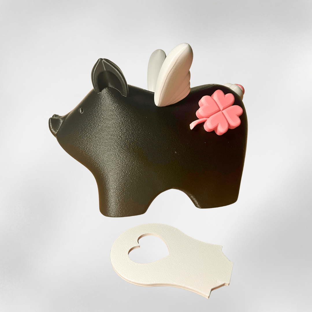 Schwarzes Sparschwein „Mathilde“ mit weißen Flügeln als liebevolle Kinderzimmer-Deko, platziert auf einem Holzregal mit warmem Licht – 3D-Druck aus dem Zauberwerk Onlineshop in Mittelhessen.