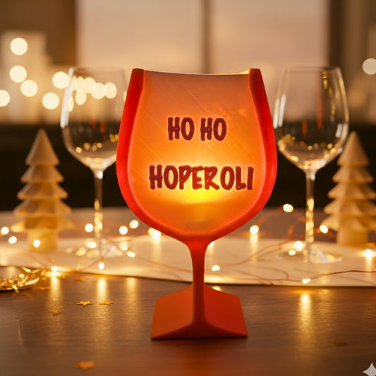 3D-gedruckte Weihnachtsdeko in Aperol-Optik, orangefarbenes Glas mit Schriftzug „Ho Ho Hoperoli“, leuchtend und festlich.